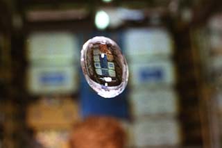 STS-84 Mission Specialists Jean-Francois Clervoy and Elena Kondakova study the effects of microgravity on a free-floating water bubble in the Spacehab.